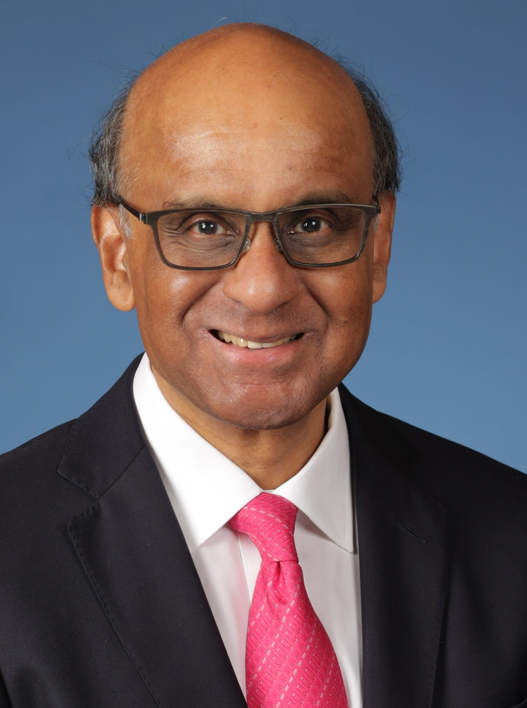 Portrait of Singapore President, Tharman Shanmugaratnam in glasses, black suit, white shirt and pink tie, smiling.